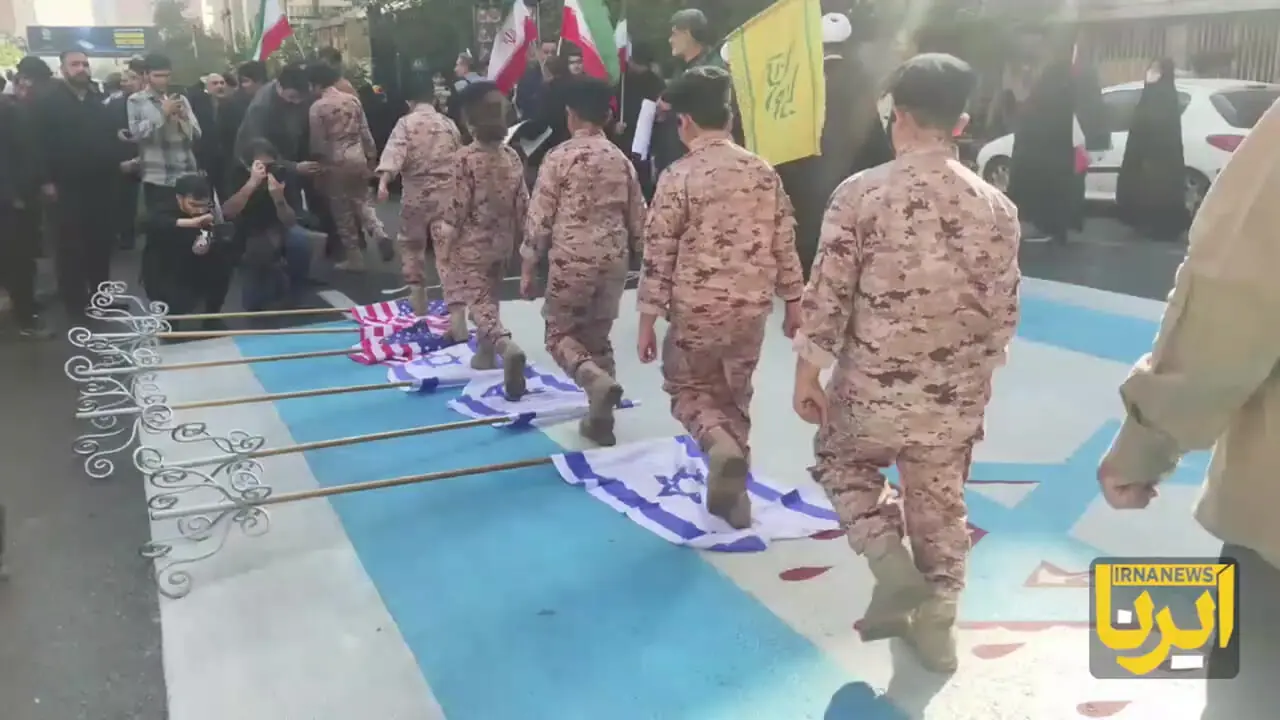 عبور دانش‌آموزان با لباس رزم از روی پرچم آمریکا و رژیم صهیونی